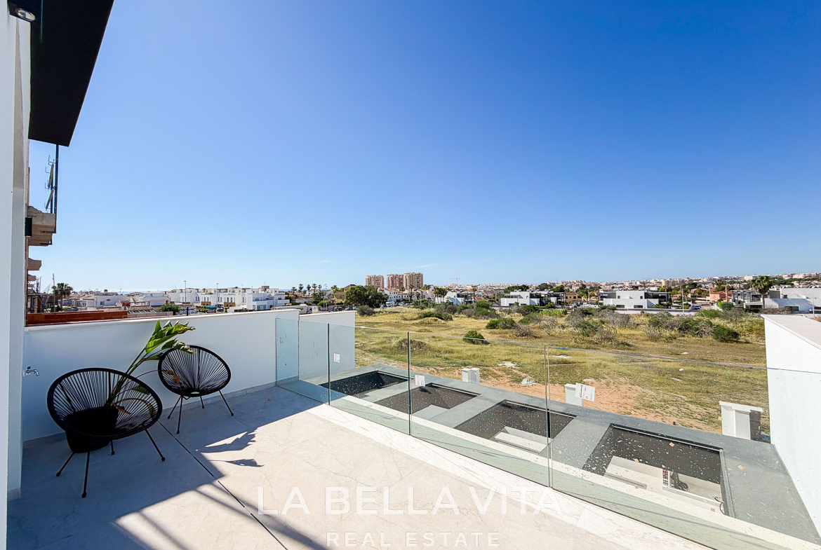 Sun-drenched terrace with modern glass railing and seating overlooking expansive views at new build villas in Aguas Nuevas, Torrevieja