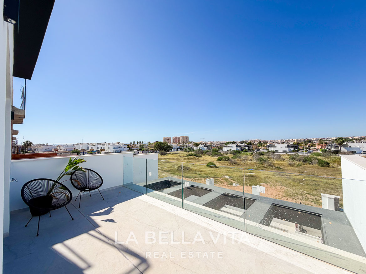 Sun-drenched terrace with modern glass railing and seating overlooking expansive views at new build villas in Aguas Nuevas, Torrevieja