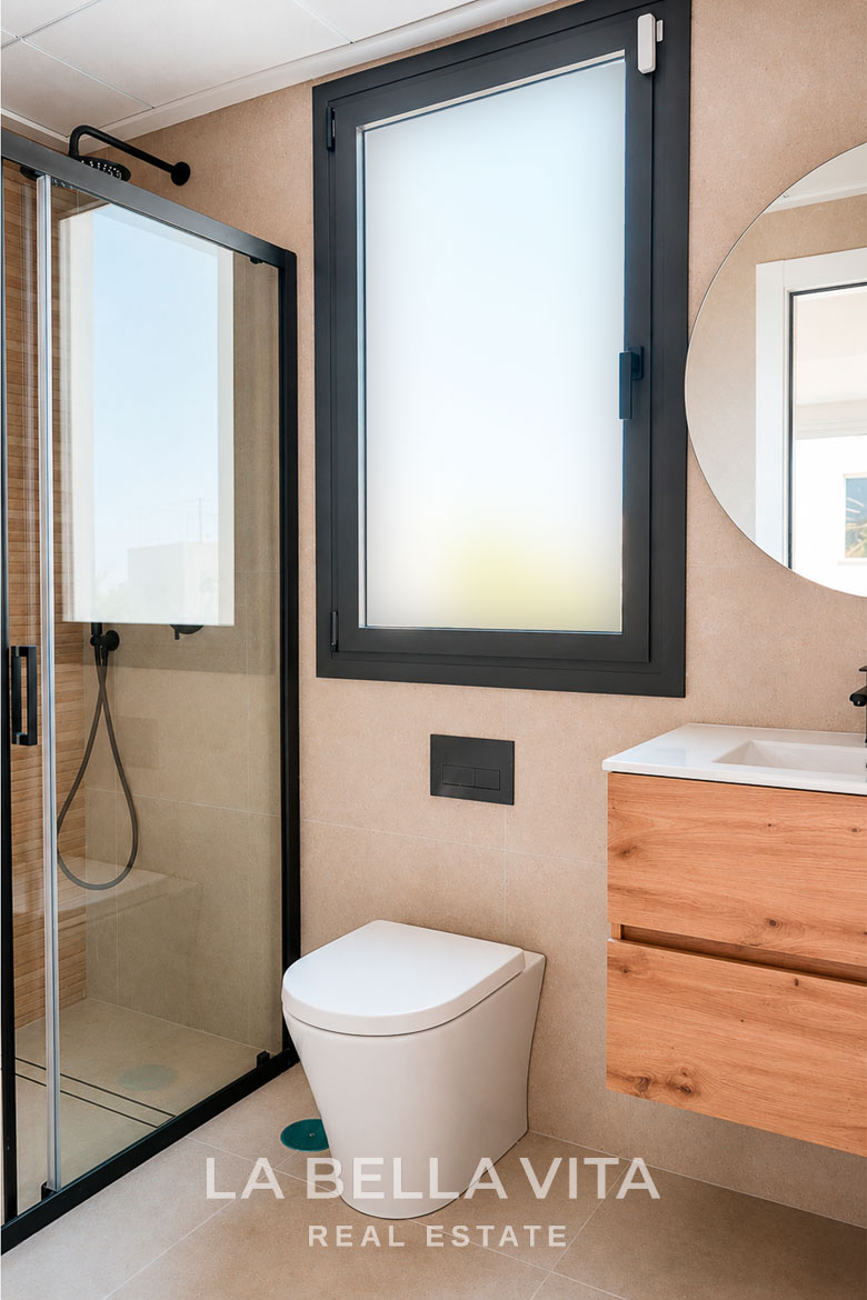 Modern, bright bathroom with sleek glass shower and wood vanity in key-ready single-storey villa in Los Montesinos, Costa Blanca