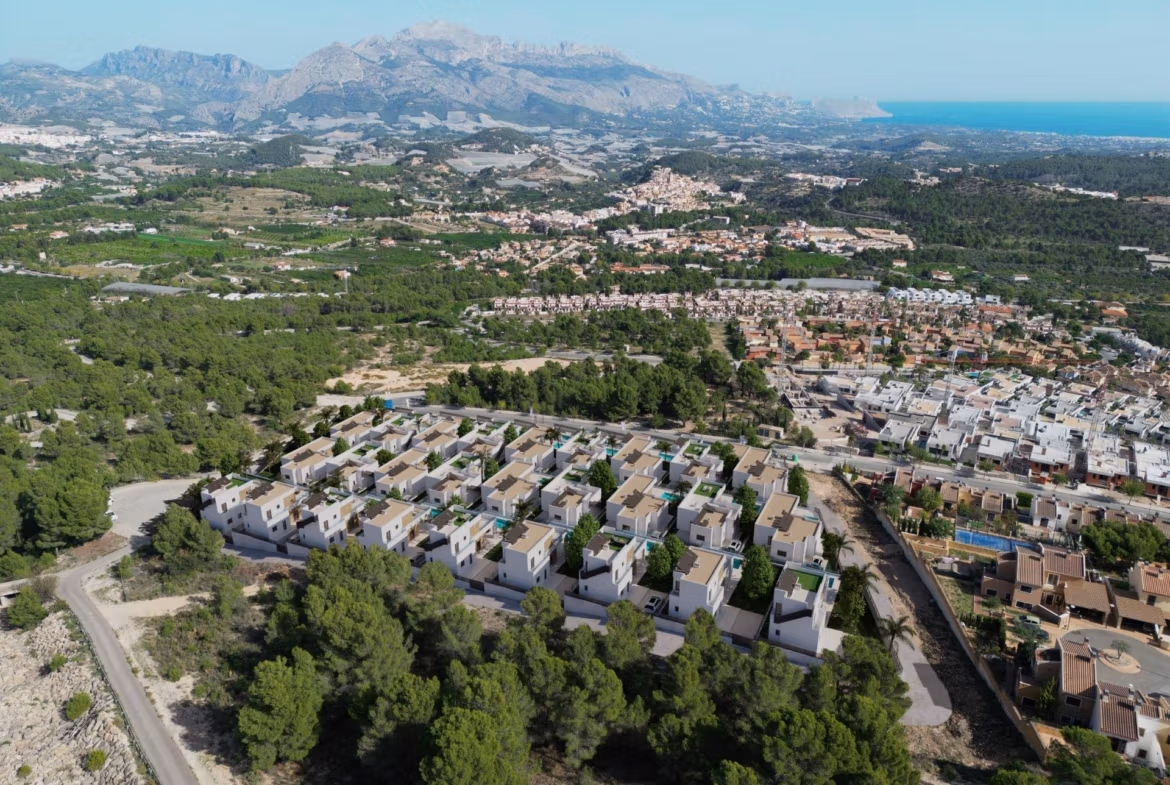 Stunning-New-Build-Villas-in-Polop-with-Sea-Views-38 Aerial view of new build villas with white facades and private pools near green forested area in Polop with sea and mountains in background