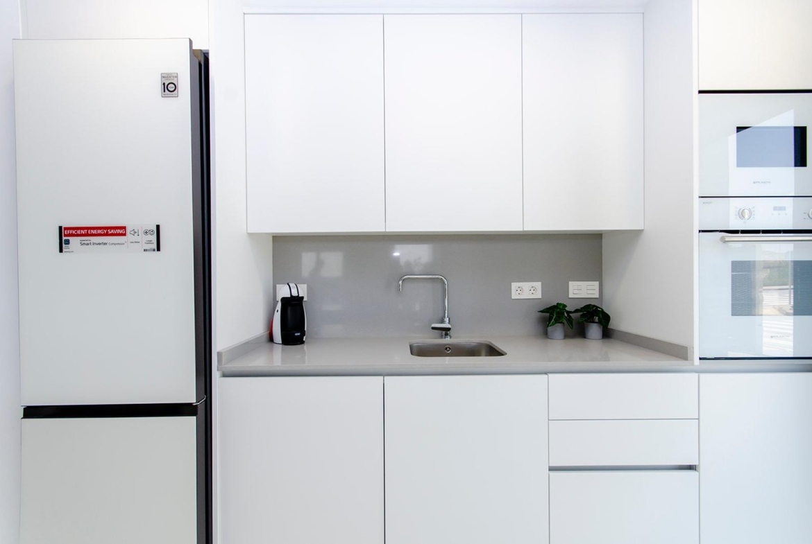 Modern white kitchen with built-in appliances in a new semi-detached villa at Vistabella Golf Resort