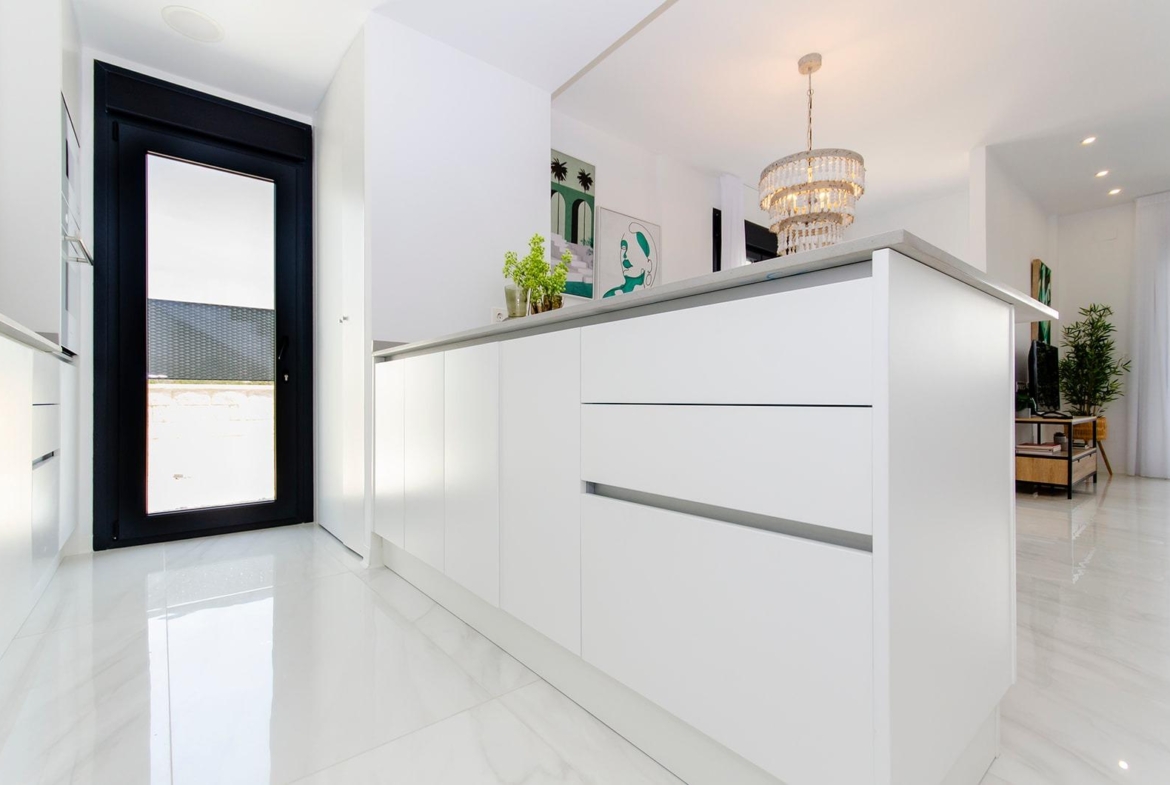 Bright modern kitchen in a new build semi-detached villa at Vistabella Golf Resort with white cabinets and marble floors