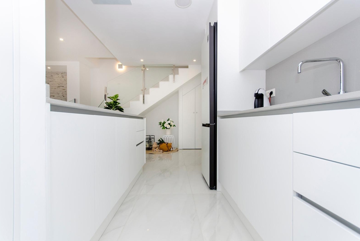 Bright modern kitchen with white cabinets and marble floor in a new build semi-detached villa at Vistabella Golf Resort