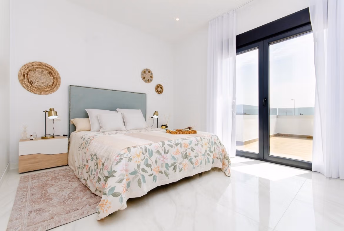 Luxury-New-Build-Semi-Detached-Villas-at-Vistabella-Golf-Resort-26 Bright bedroom with floral bedspread and large glass doors in a new build semi-detached villa at Vistabella Golf Resort