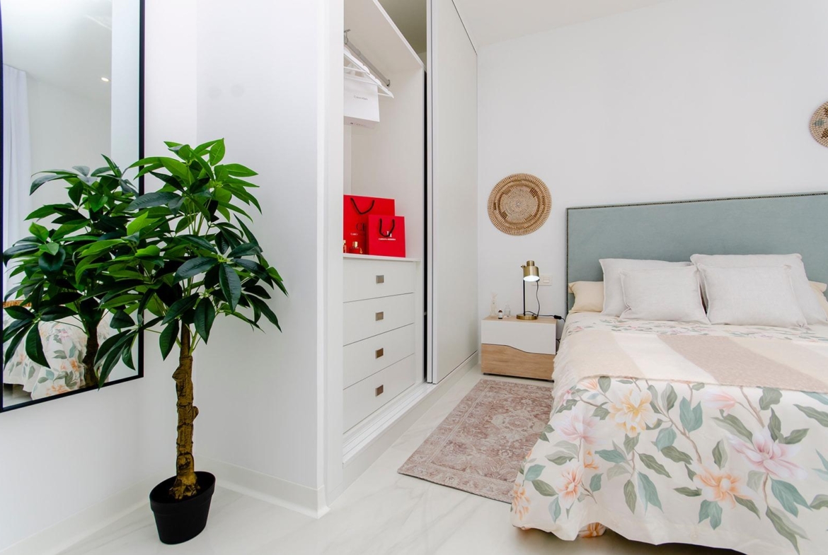 Bedroom with built-in wardrobe and decorative plant in new build semi-detached villa at Vistabella Golf Resort