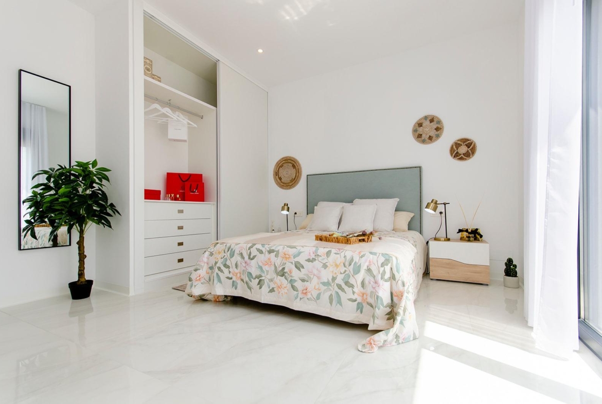 Bright bedroom with double bed, built-in wardrobe, and balcony in a new semi-detached villa at Vistabella Golf Resort