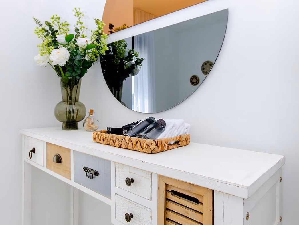 Luxury-New-Build-Semi-Detached-Villas-at-Vistabella-Golf-Resort-33 White wooden console table with decorative items and a round two-tone mirror in a semi-detached villa interior at Vistabella Golf Resort