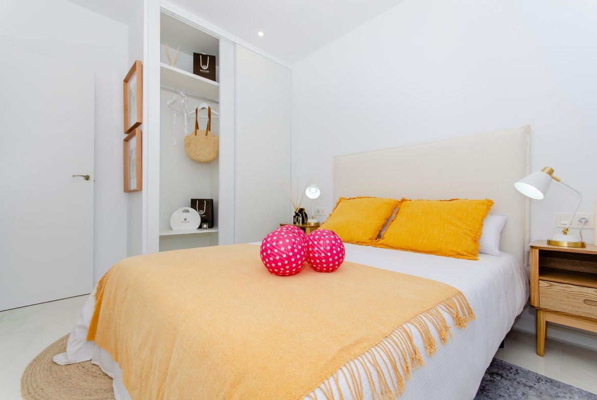 Bright bedroom with double bed and open wardrobe in new build semi-detached villa at Vistabella Golf Resort.