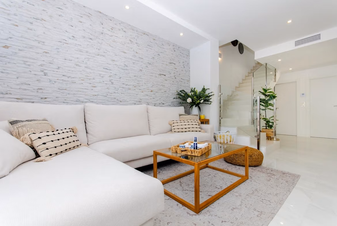 Luxury-New-Build-Semi-Detached-Villas-at-Vistabella-Golf-Resort-42 Bright living room with white sofa, glass coffee table, and staircase in a semi-detached villa in Vistabella Golf Resort.