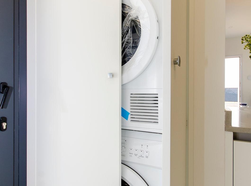 Laundry area with stacked washer and dryer inside a stylish new build semi-detached villa in Vistabella Golf Resort.