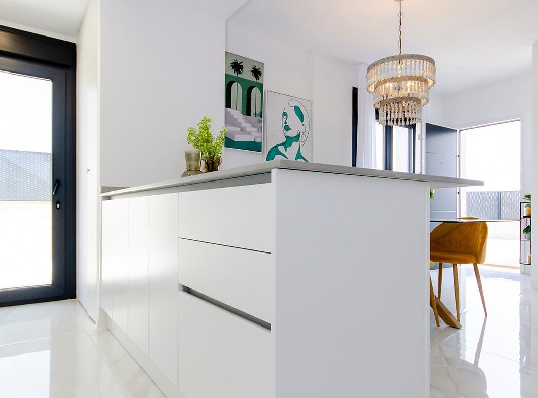 Bright modern kitchen with white island and dining area in new semi-detached villa at Vistabella Golf Resort