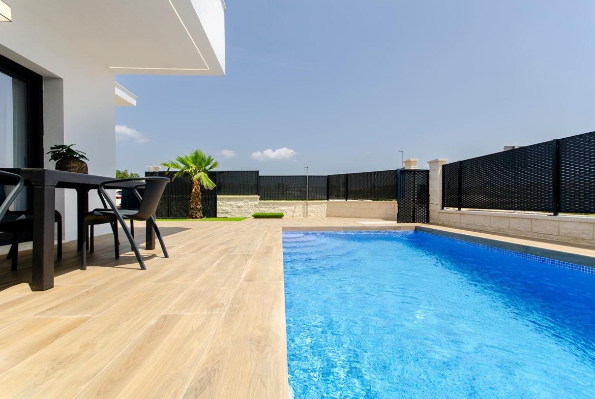 Private pool and terrace area of a new build semi-detached villa at Vistabella Golf Resort with outdoor seating and clear sky.