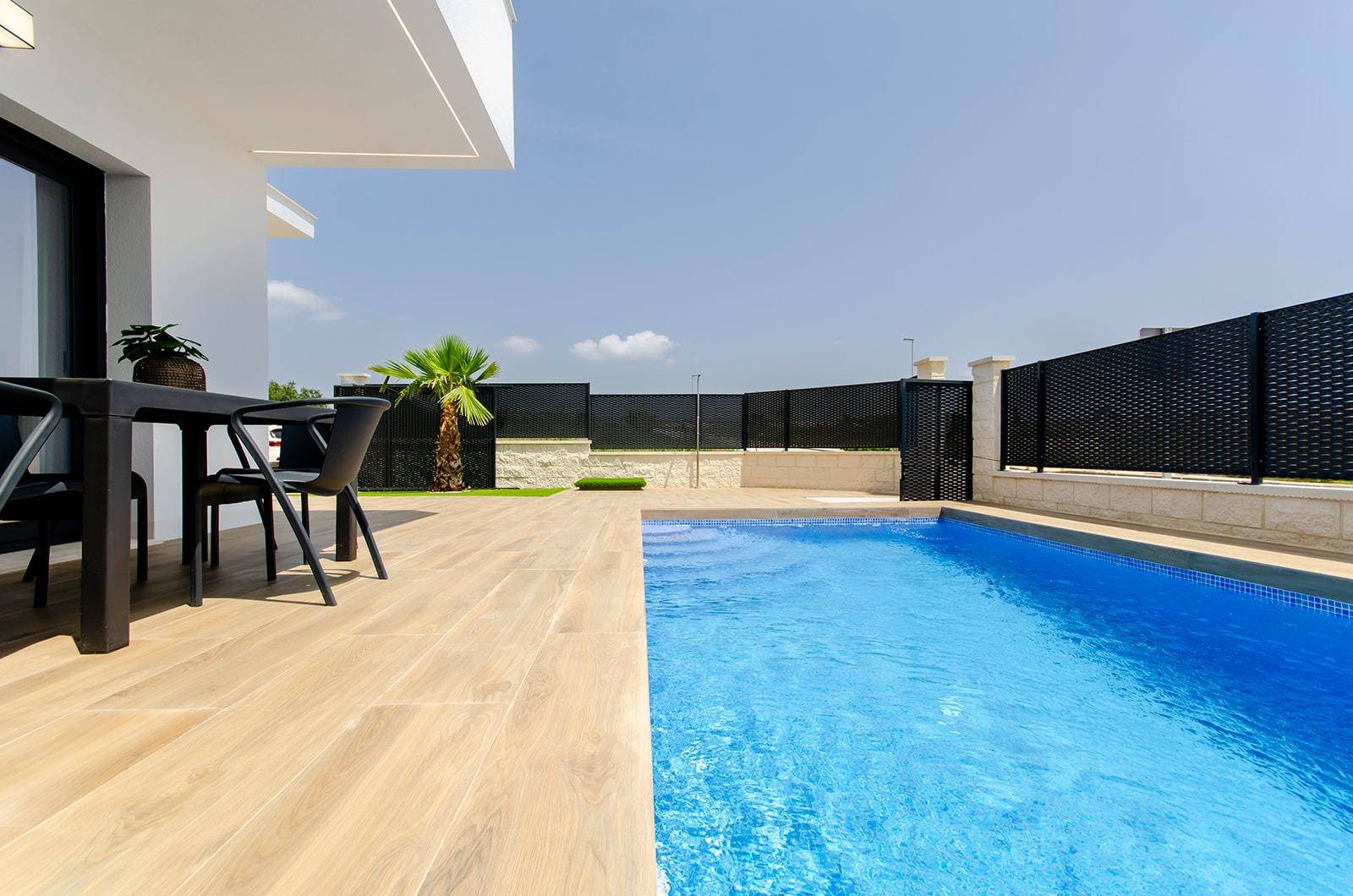 Private pool and terrace area of a new build semi-detached villa at Vistabella Golf Resort with outdoor seating and clear sky.