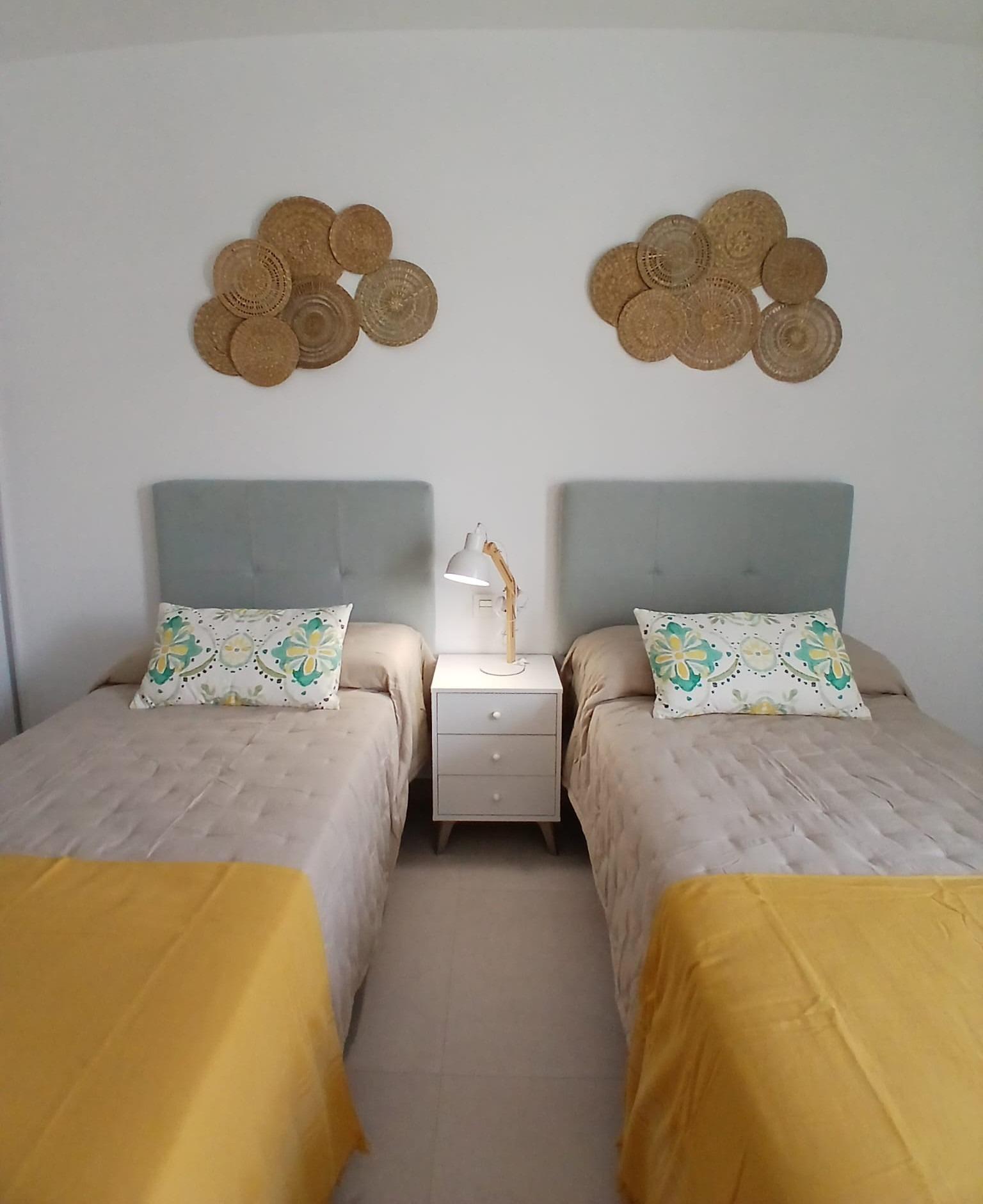 Modern-New-Build-Quad-Villas-in-Bigastro-Alicante-11 Twin beds with yellow throws and decorative pillows in a bedroom of a new build quad villa in Bigastro, Alicante.