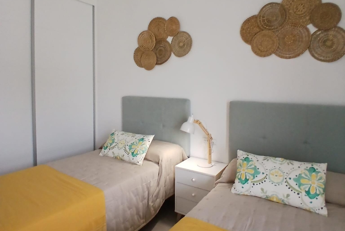 Twin bedroom with yellow bedding and decorative wall accents in new build quad villa in Bigastro, Alicante.