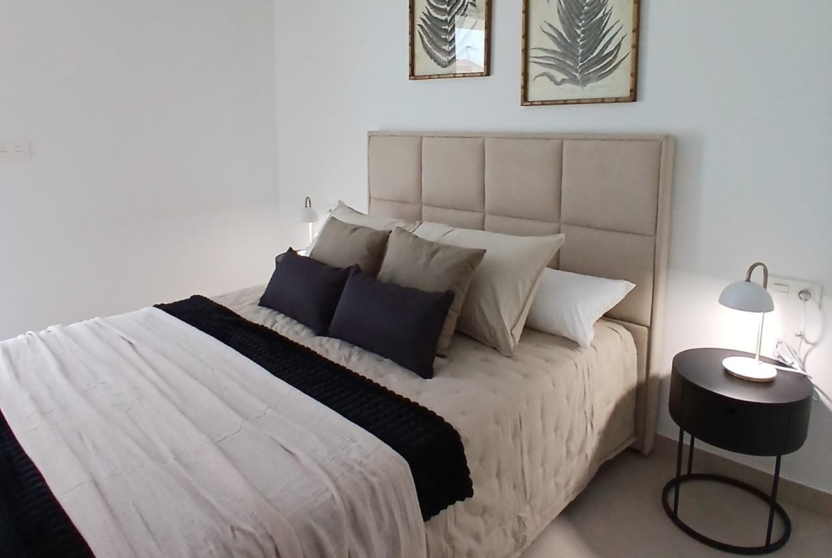 Bedroom with beige upholstered bed and modern decor in new build quad property in Bigastro, Alicante