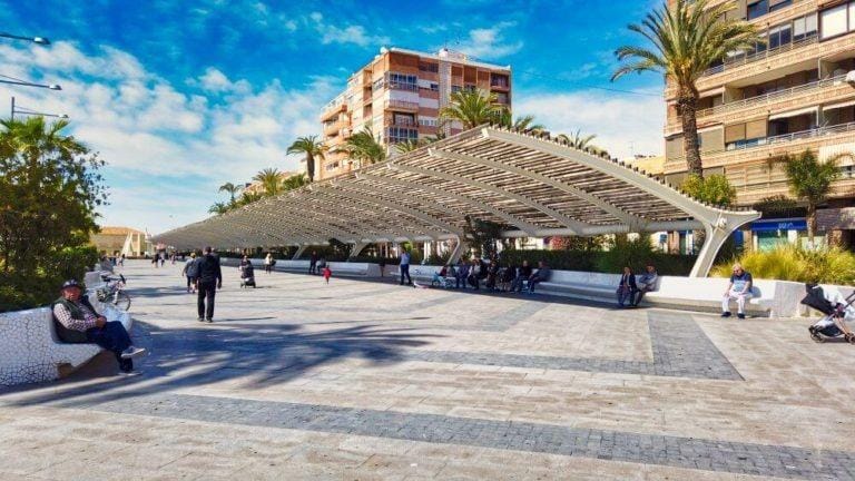 Open plaza with modern shaded seating area near residential buildings in Torrevieja near the beach, complementing the penthouse location.