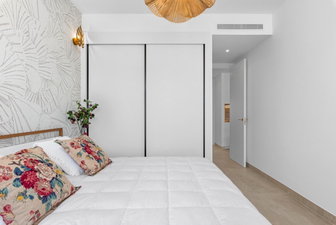 Bright bedroom with floral cushions and patterned wall in a new build 4 bedroom ground floor apartment in Benijofar.
