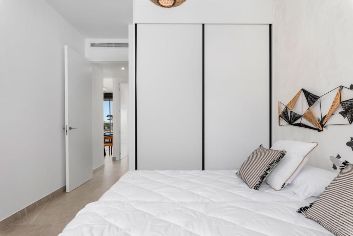 Bright bedroom with white bedding and modern decor in a 2 bedroom penthouse for sale in Benijofar.