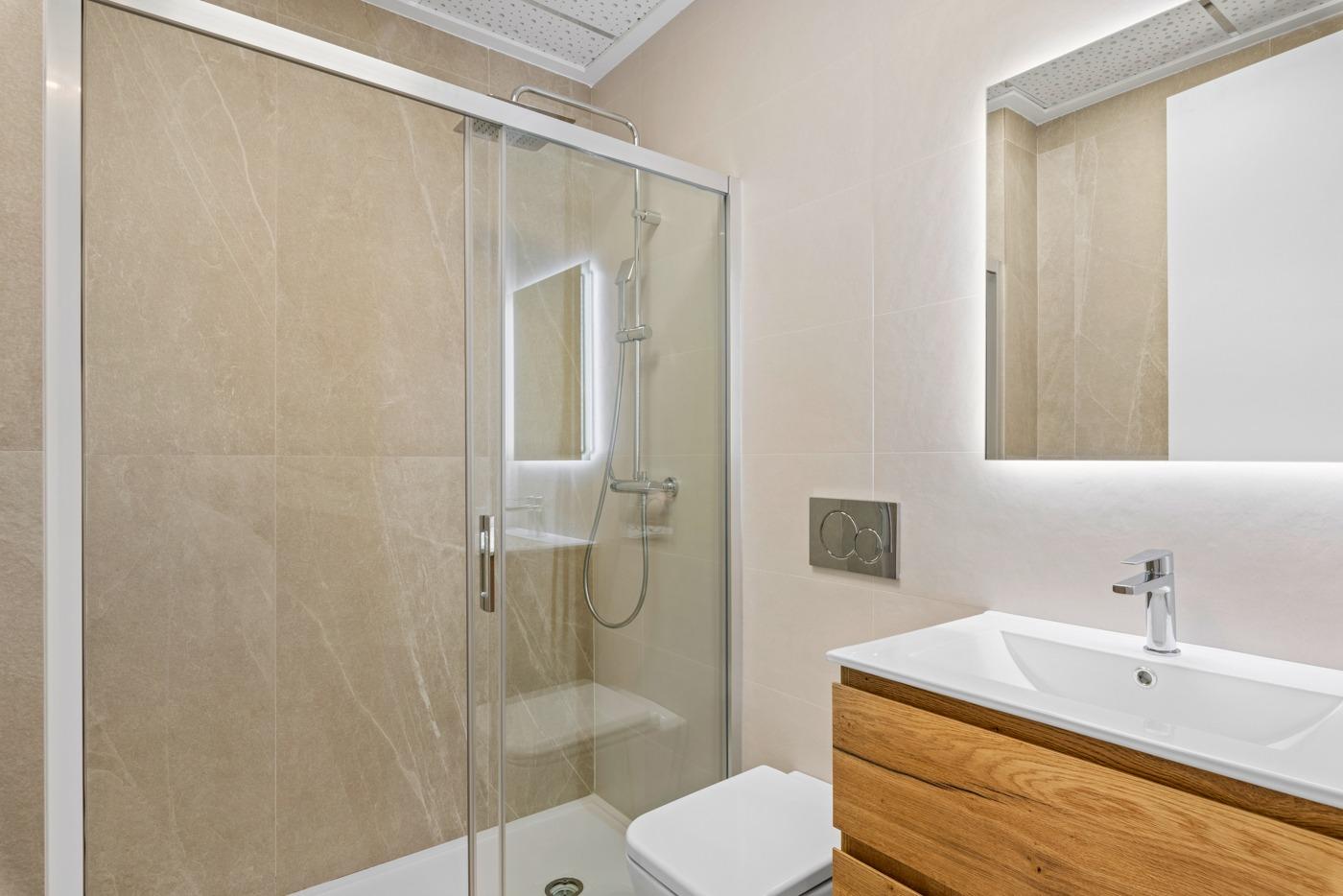 NEW-BUILD-BUILD-RESIDENTIAL-COMPLEX-IN-BENIJOFAR-18 Modern bathroom with glass shower and wooden vanity in a new build 4-bedroom ground floor apartment in Benijofar.