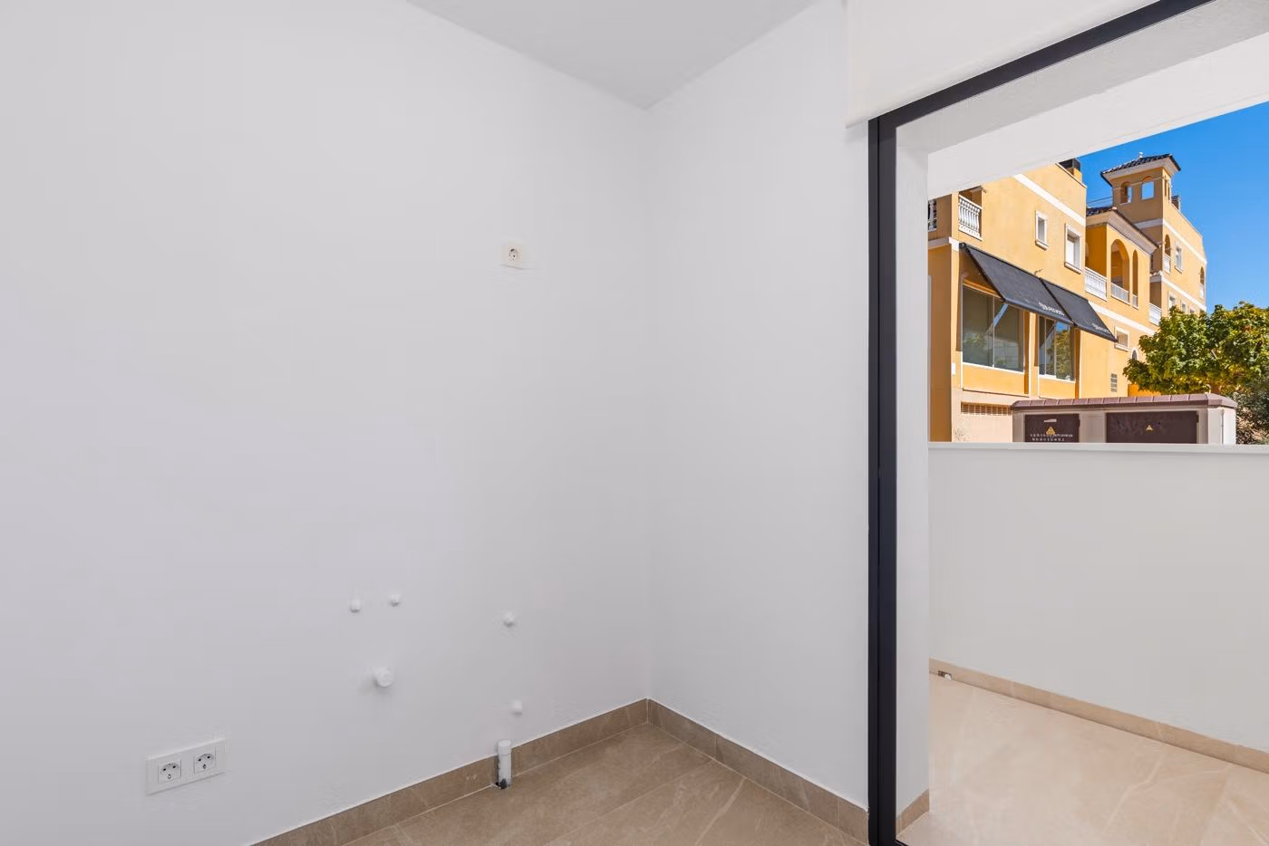 Empty corner space with tiled floor and sliding door opening to a balcony in a modern 3-bedroom apartment in Benijofar, Costa Blanca South