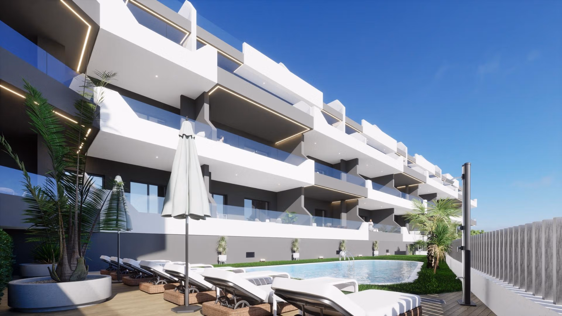 Outdoor pool and sun loungers at bright new build 2 bedroom apartment complex in Benijofar, Alicante under clear blue sky.