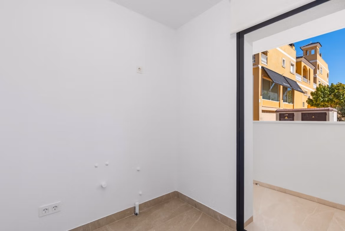 Small empty utility room with tiled floor and access to balcony in a 2 bedroom apartment in Benijofar, Alicante.