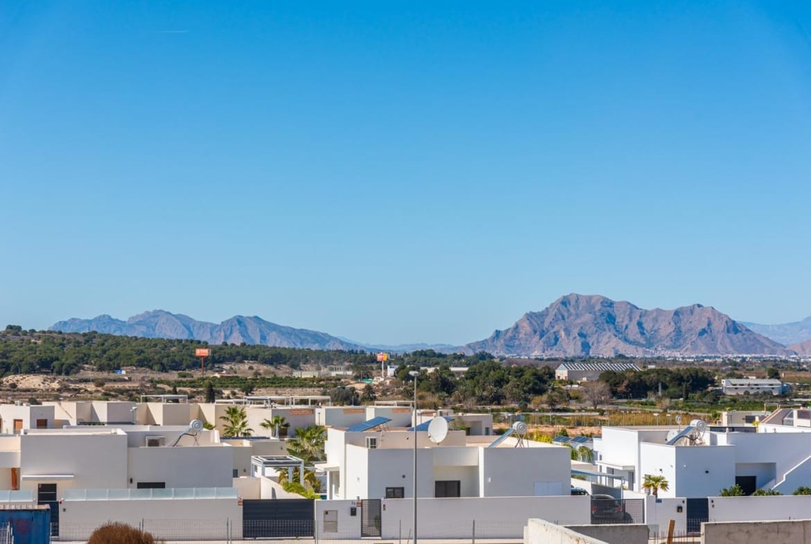 White modern 2 bedroom apartment complex in Benijofar, Alicante with mountainous landscape under clear blue sky