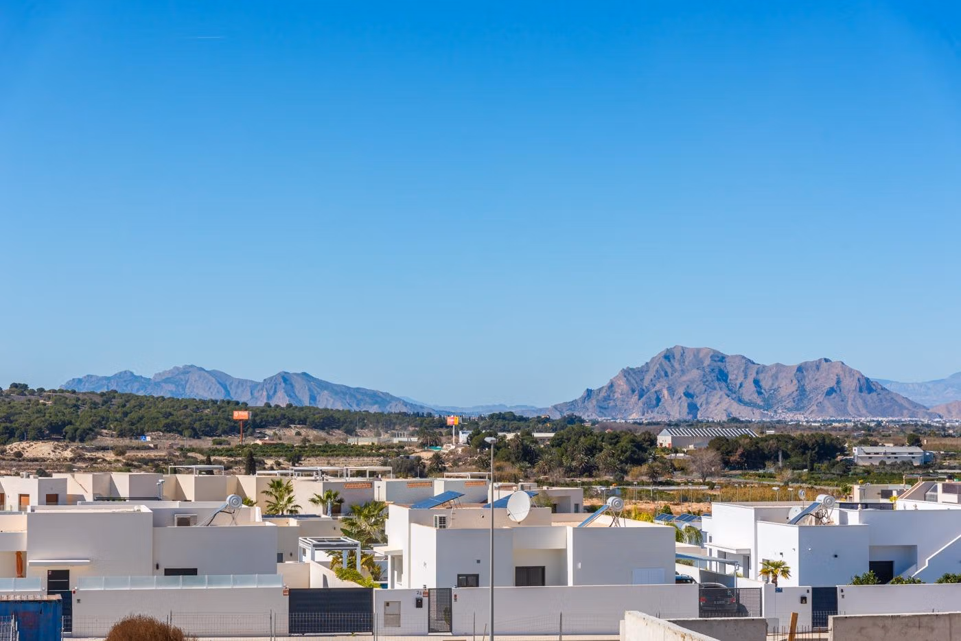 White modern 2 bedroom apartment complex in Benijofar, Alicante with mountainous landscape under clear blue sky