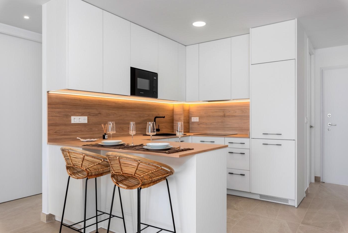 Modern kitchen with breakfast bar and wicker stools in a new build 3-bedroom ground floor apartment in Benijofar