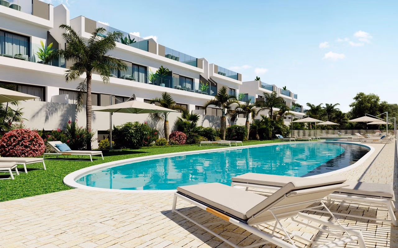 NEW-BUILD-RESIDENCIAL-IN-LOS-BALCONES-TORREVIEJA-9 Large outdoor pool with sun loungers and umbrellas in front of modern top floor apartments in Los Balcones, Torrevieja.
