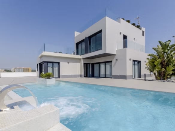 Modern two-story villa with large windows, terrace, private pool, and clear sky in a coastal setting in Campoamor.