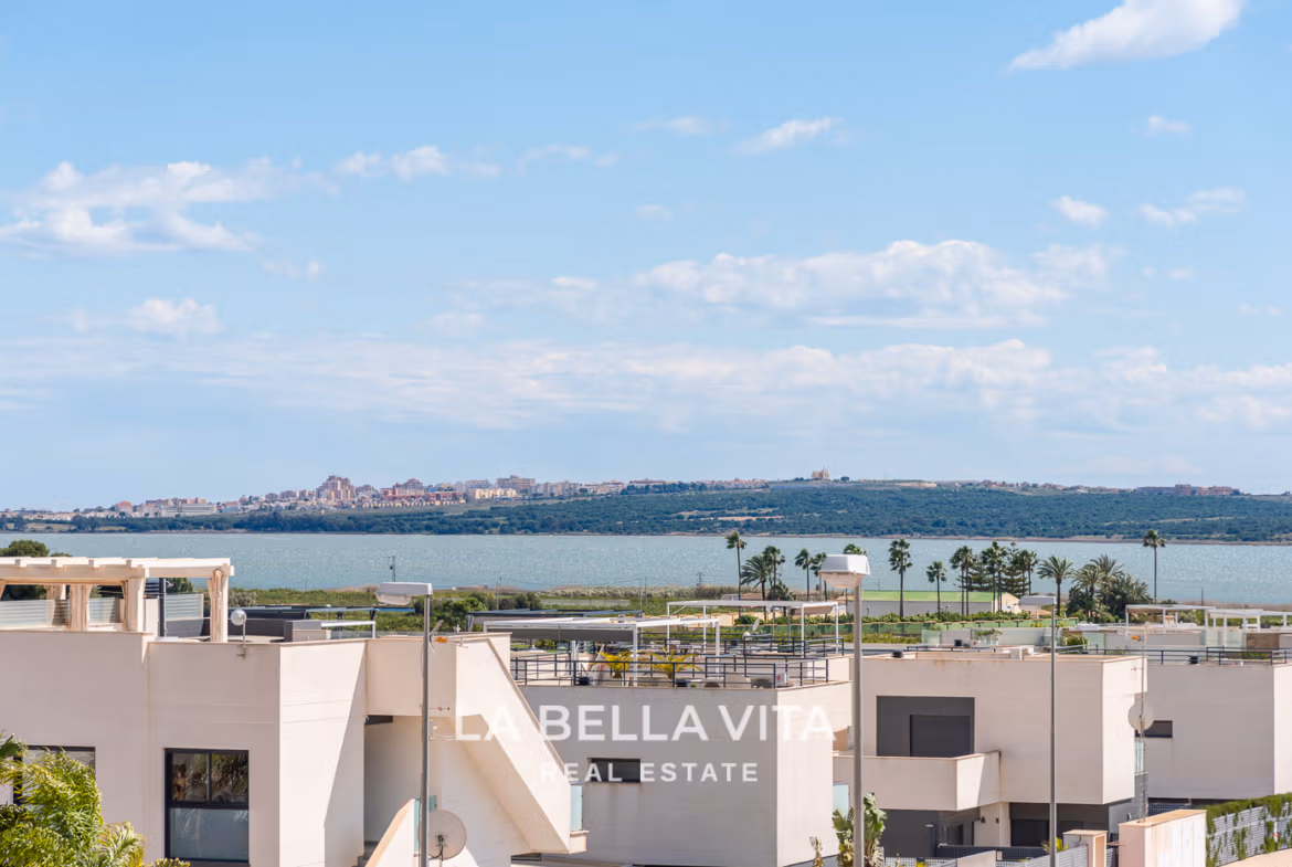 Modern villa exterior with rooftop solarium and views of lake and palm trees in Ciudad Quesada