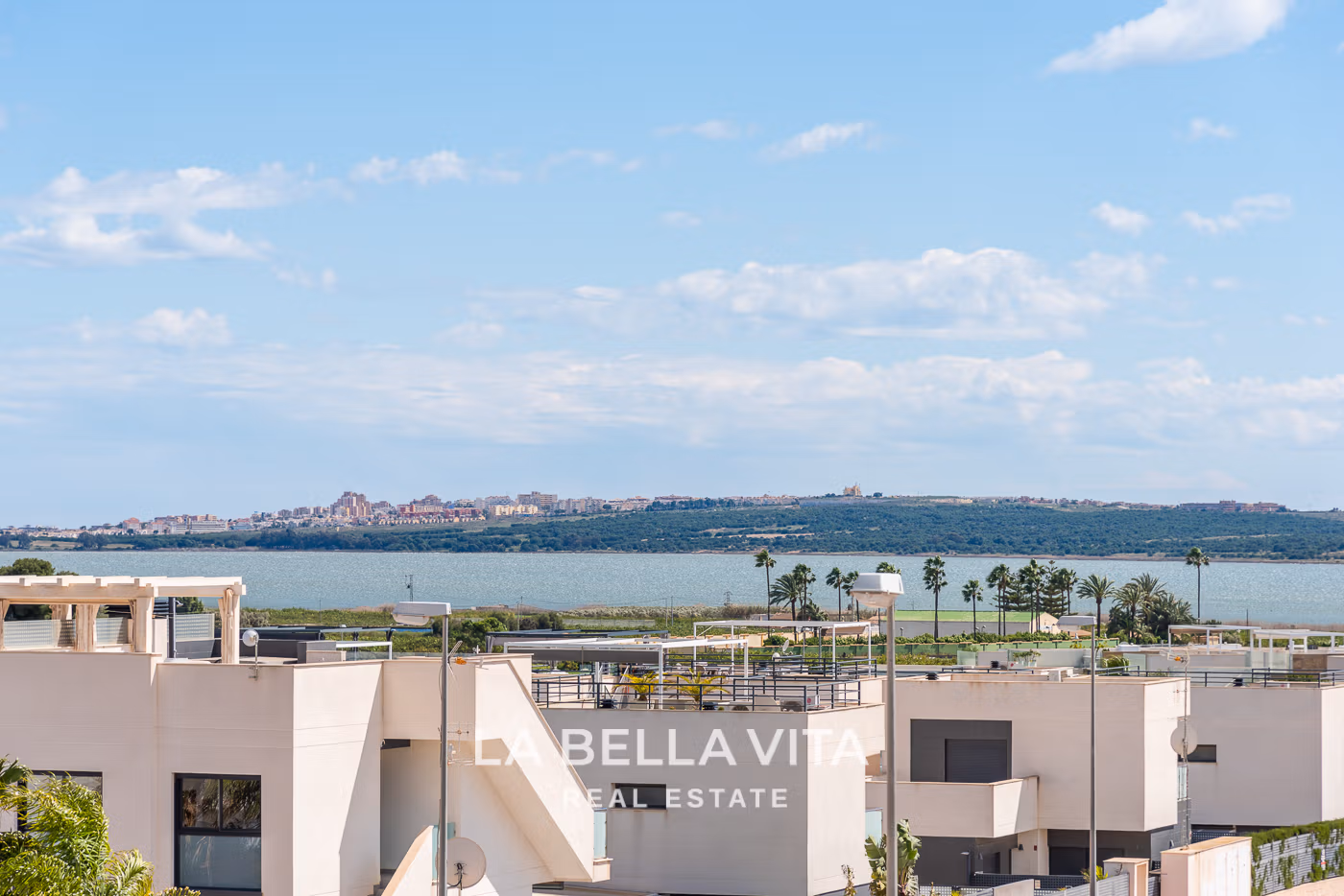 Modern villa exterior with rooftop solarium and views of lake and palm trees in Ciudad Quesada