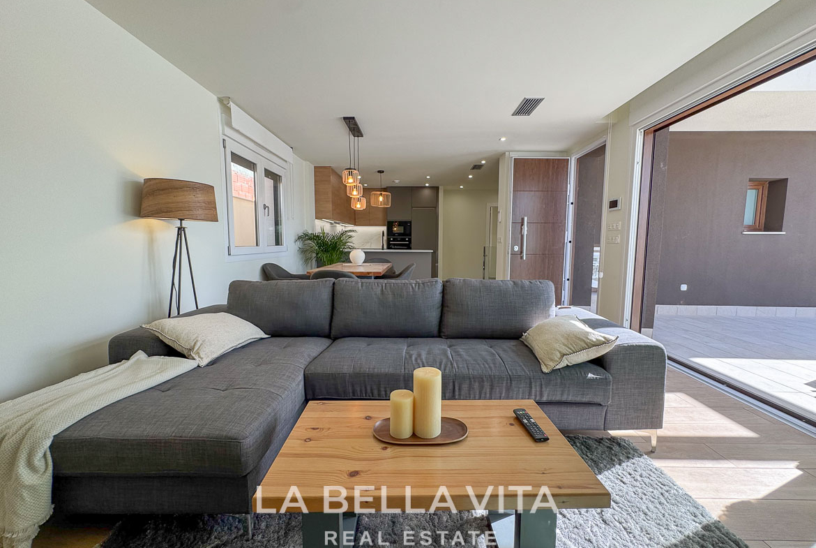 Bright, modern open-plan living area with plush sofa and sliding doors leading to terrace in elegant Benijófar villa.