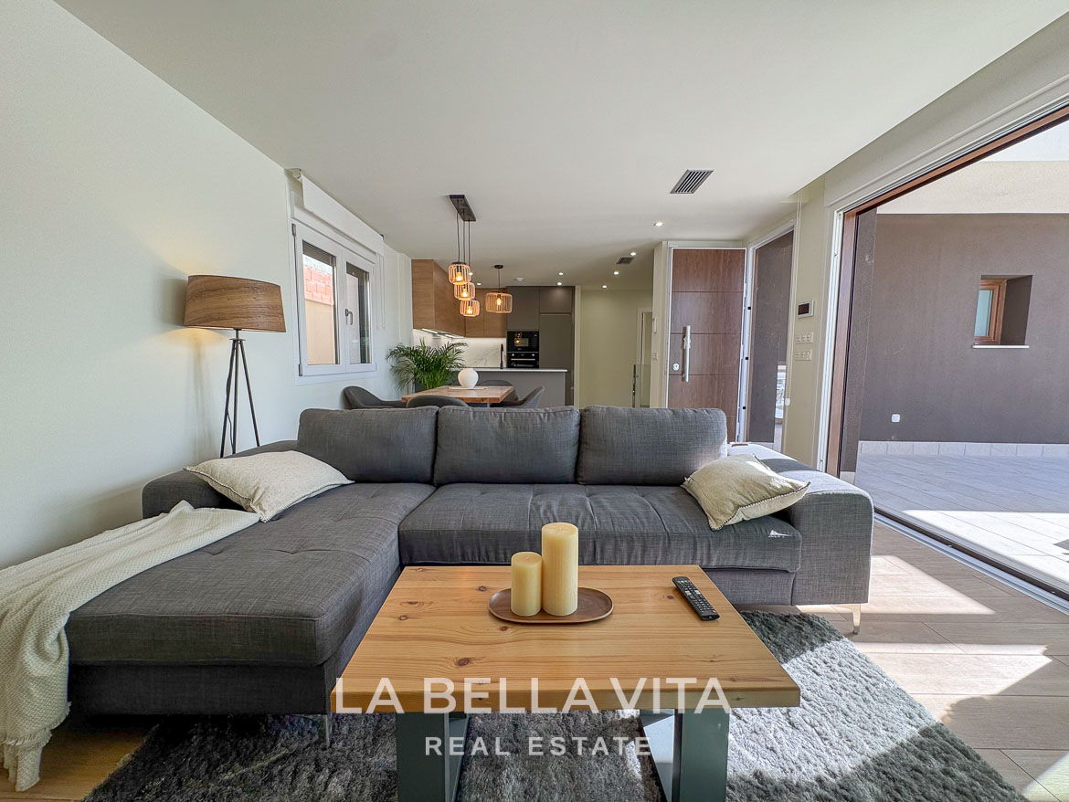 Bright, modern open-plan living area with plush sofa and sliding doors leading to terrace in elegant Benijófar villa.
