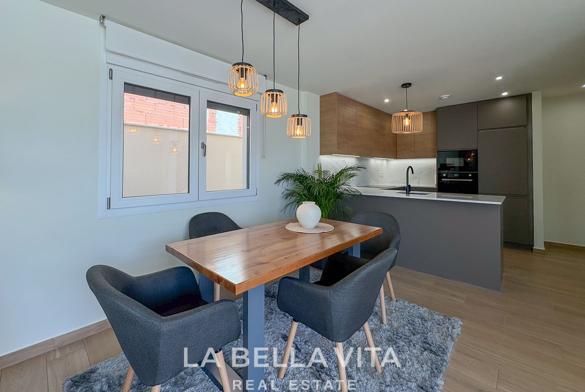 Bright, modern dining area with stylish lighting and sleek kitchen in elegant single-storey villa for sale in Benijófar, Costa Blanca