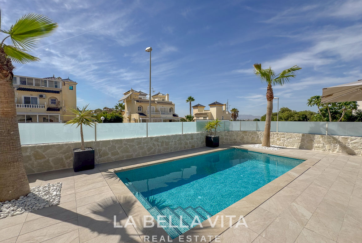 Sun-drenched private pool with modern tiled terrace and palm trees in elegant single-storey villa, Benijófar, Costa Blanca.