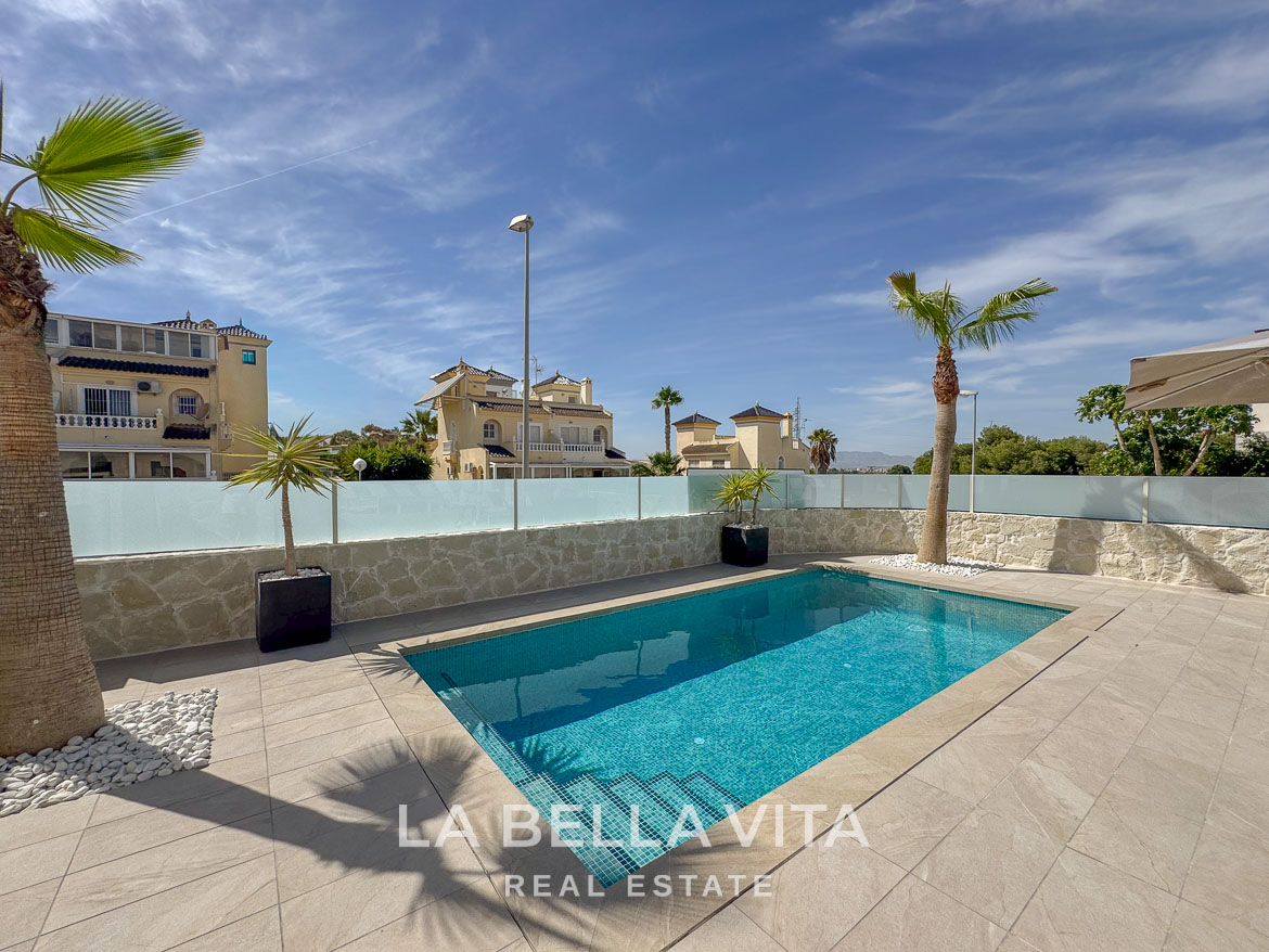 Sun-drenched private pool with modern tiled terrace and palm trees in elegant single-storey villa, Benijófar, Costa Blanca.