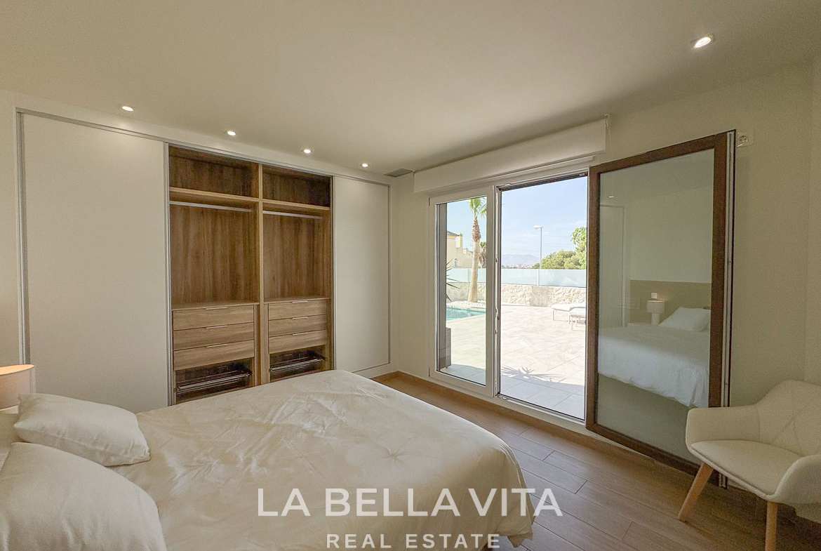 Bright and serene bedroom with modern built-in wardrobe and glass doors opening to sun-drenched terrace in Benijófar villa