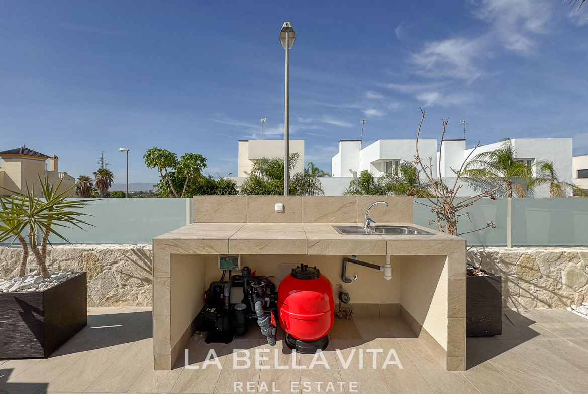 Modern outdoor kitchenette with sleek stone finish and landscaped terrace at elegant single-storey villa in Benijófar, Costa Blanca