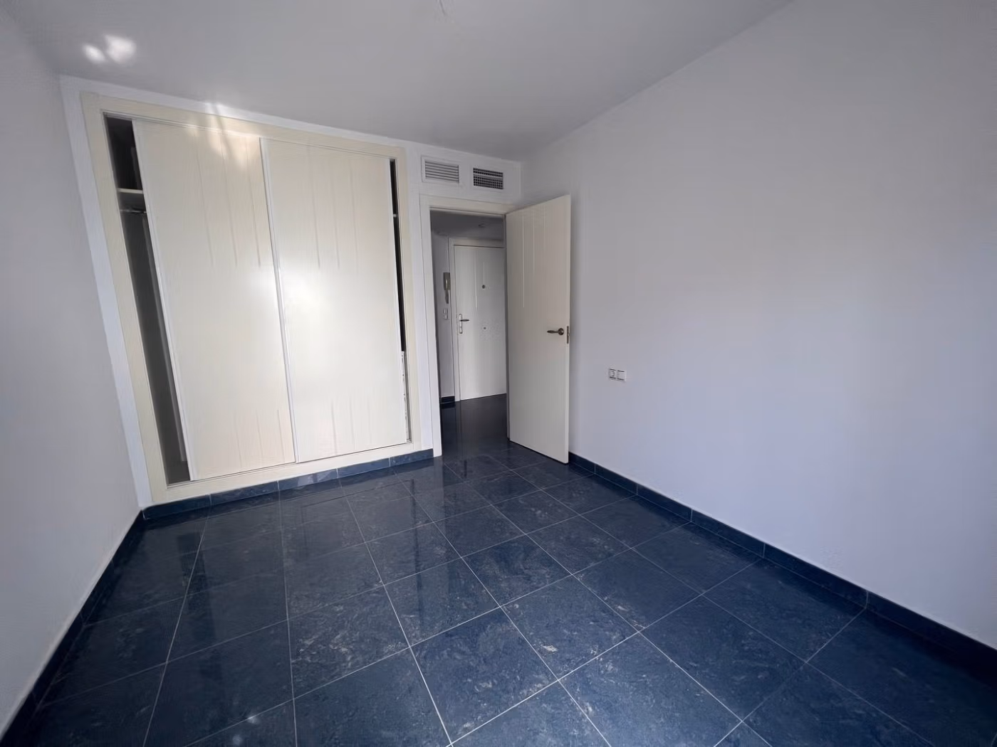 Bright, modern bedroom with sleek dark tile flooring and built-in closets in luxury 3 bedroom penthouse in Calpe