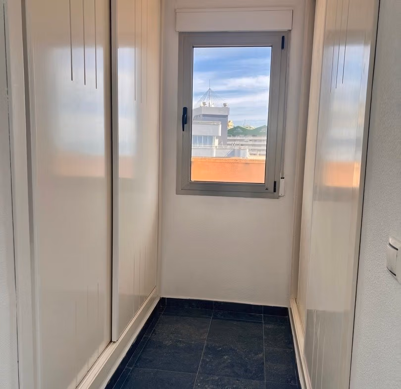 Bright and narrow walk-in closet with sleek white cabinetry in luxury 3-bedroom penthouse in Calpe.