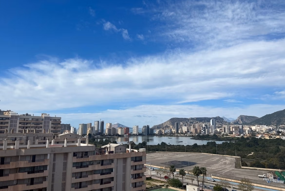 Panoramic sea view from a spacious luxury 3-bedroom penthouse solarium in bright, modern Calpe with cityscape and mountains.