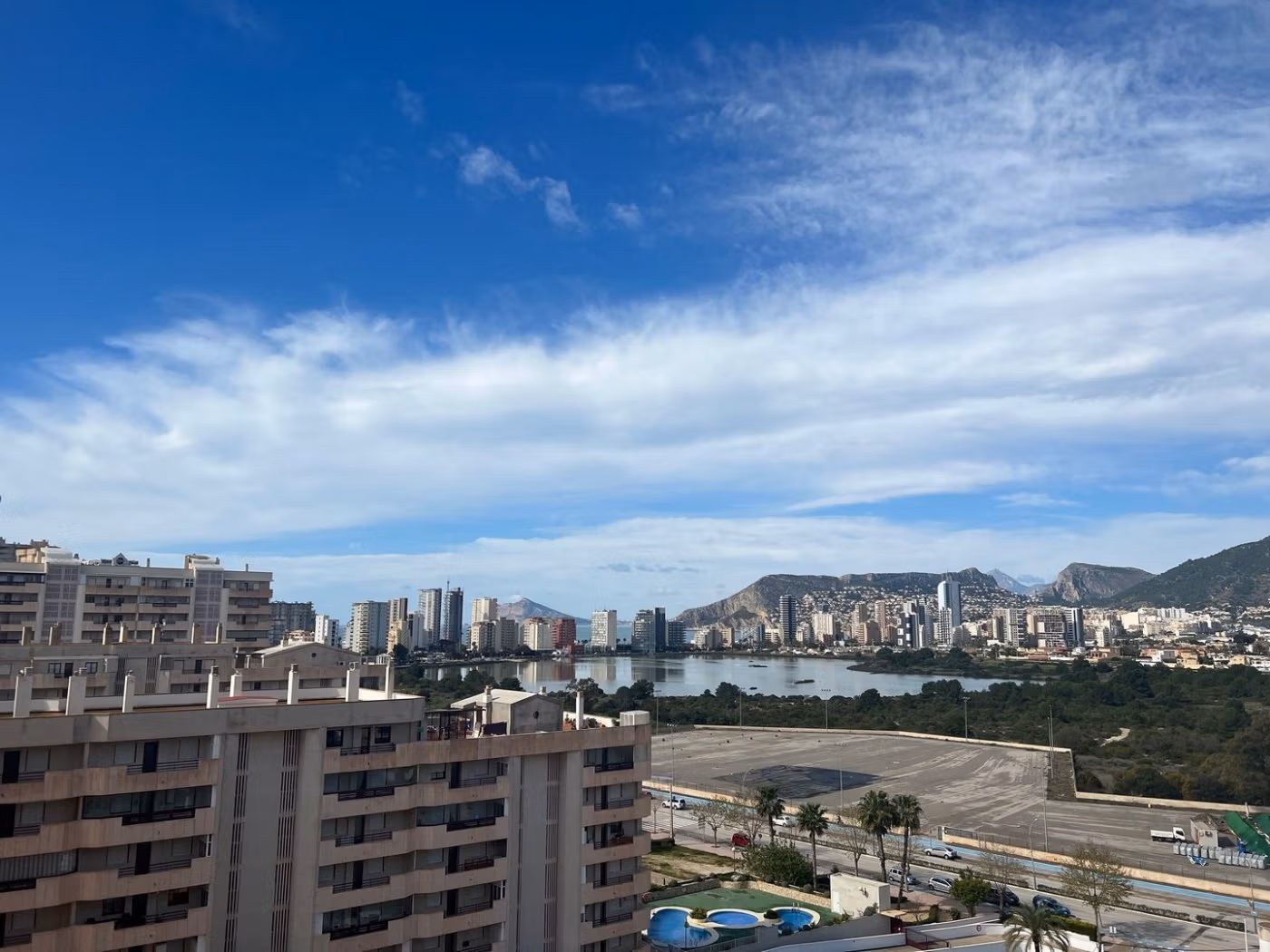 Panoramic sea view from a spacious luxury 3-bedroom penthouse solarium in bright, modern Calpe with cityscape and mountains.