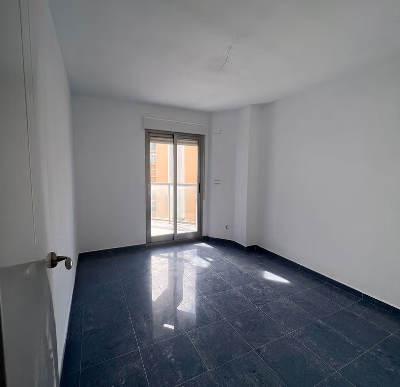 Bright spacious bedroom with dark marble flooring and balcony access in luxury 3-bedroom penthouse for sale in Calpe.