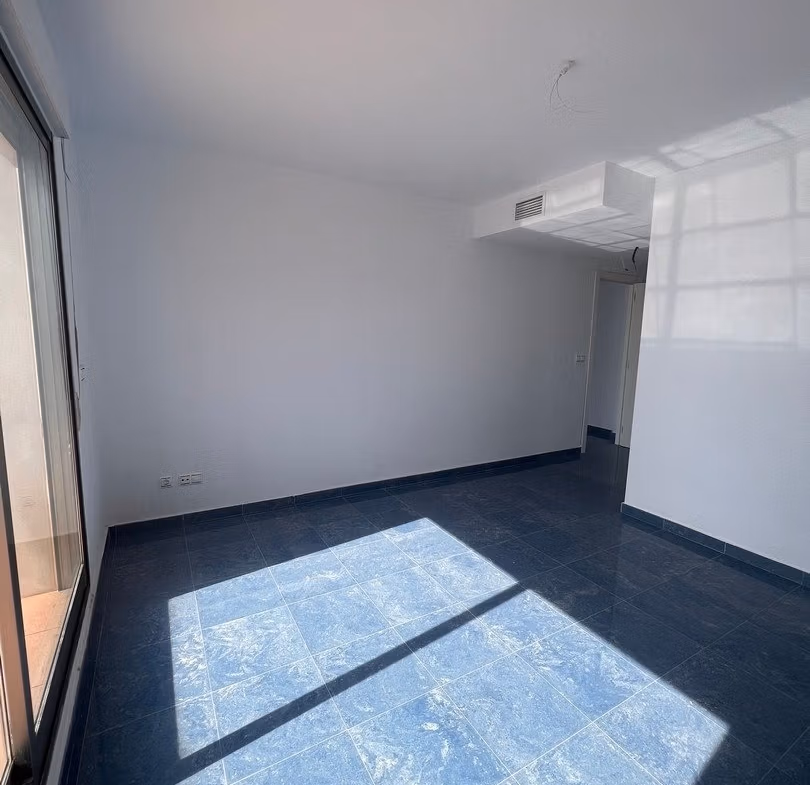 Bright spacious living room with large windows in luxury 3 bedroom penthouse in Calpe, featuring sleek blue tiled floors and sea views.