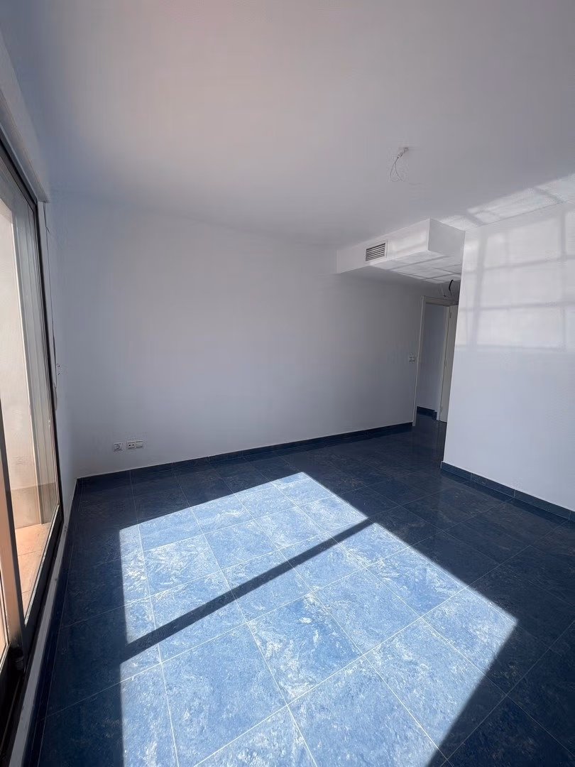 Bright spacious living room with large windows in luxury 3 bedroom penthouse in Calpe, featuring sleek blue tiled floors and sea views.