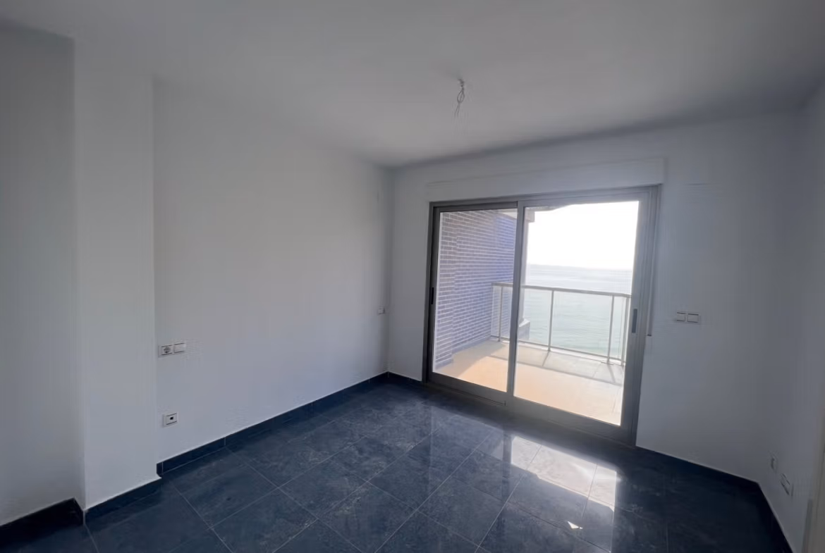 Bright, modern living space with sleek black flooring and sea views from the balcony in a luxury 3-bedroom penthouse in Calpe.