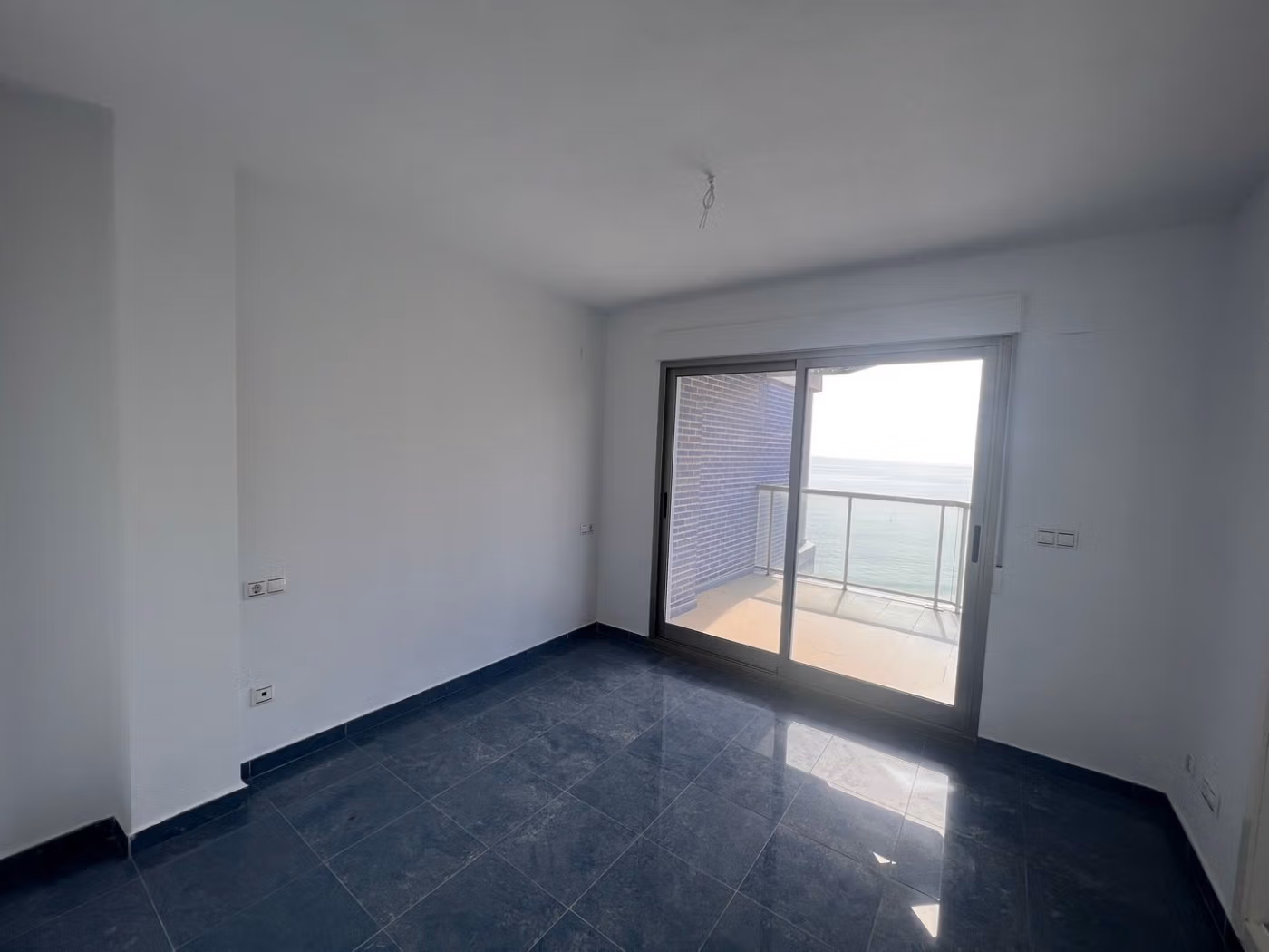 Bright, modern living space with sleek black flooring and sea views from the balcony in a luxury 3-bedroom penthouse in Calpe.